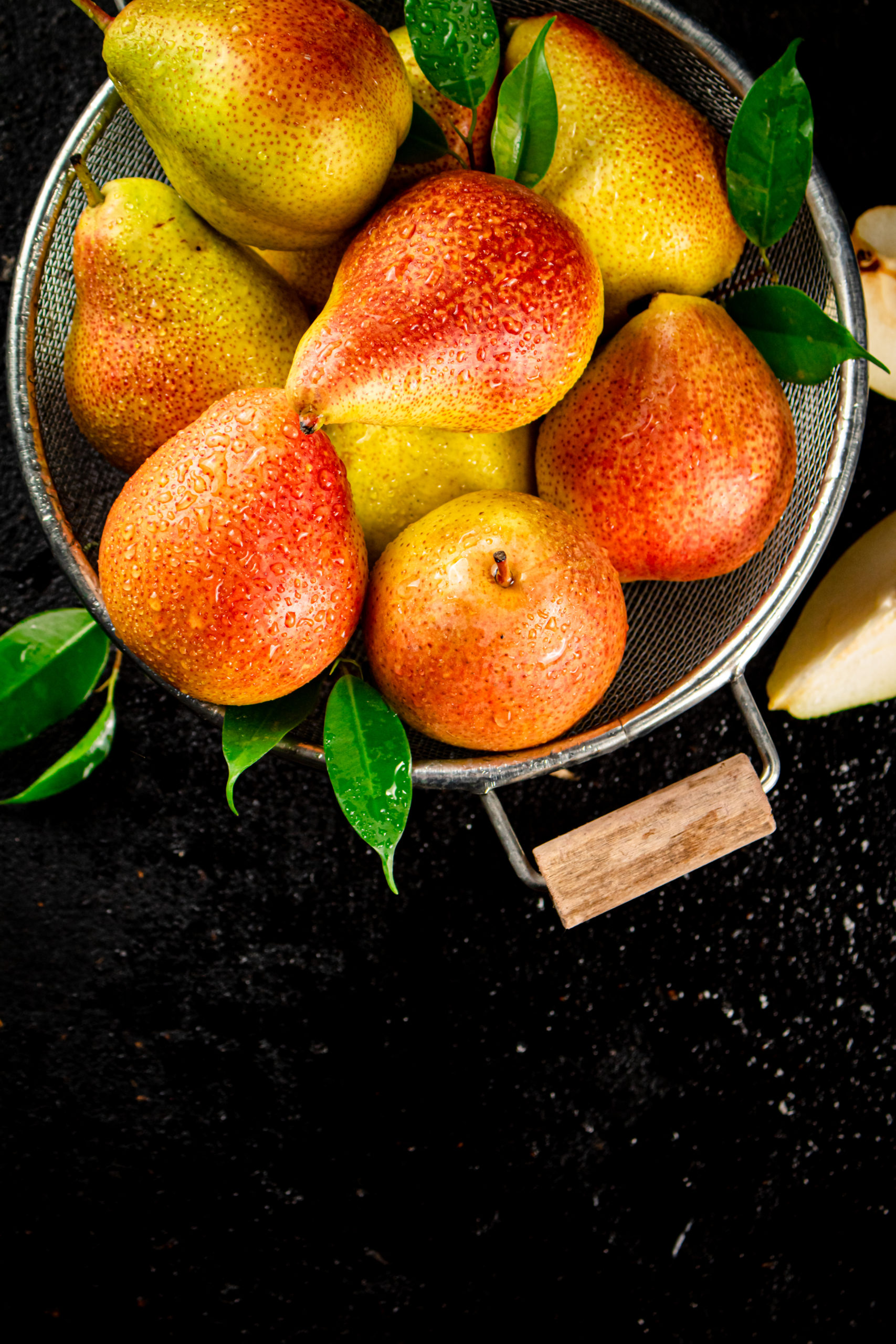 Fresh pears with leaves in a colander.