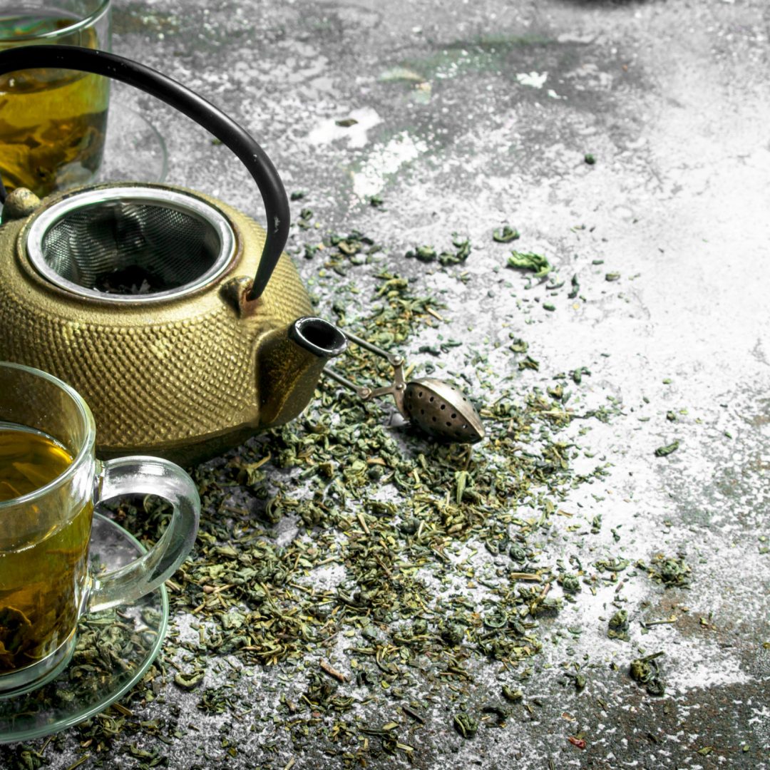 Green tea with a teapot. On a rustic background.
